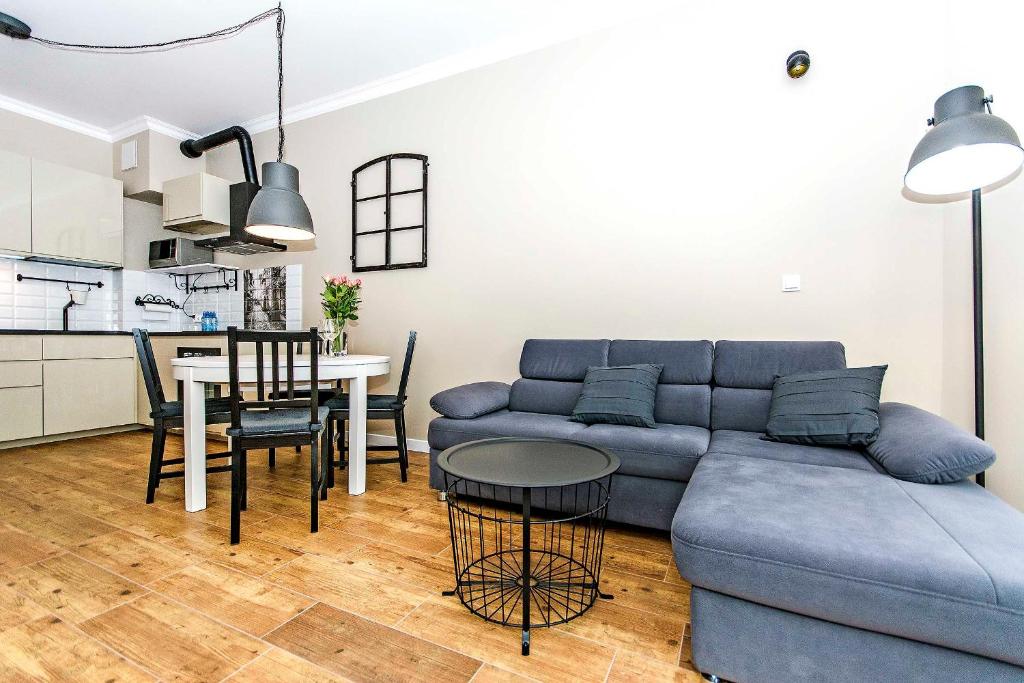 - un salon avec un canapé bleu et une table dans l'établissement Four - Neptun Park by OneApartments, à Gdańsk