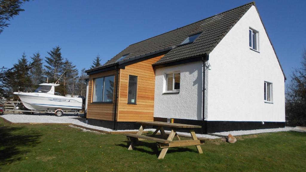 ein winziges Haus mit einem Picknicktisch und einem Boot in der Unterkunft Breakish Escape B&B-near Broadford in Breakish