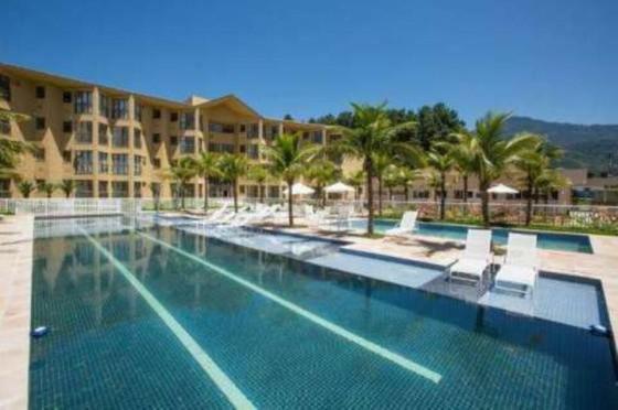 een groot zwembad met stoelen en een hotel bij Loft Aldeia dos Reis in Mangaratiba