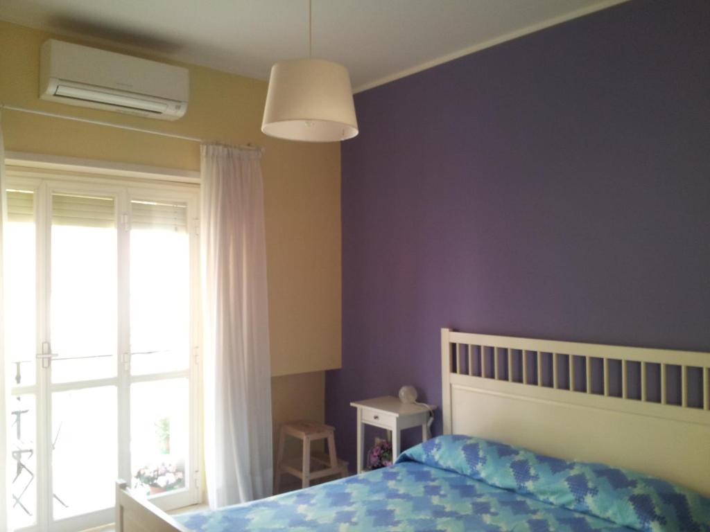 Schlafzimmer mit lila Wänden, einem Bett und einem Fenster in der Unterkunft B&B Dimora di Traiano in Terracina