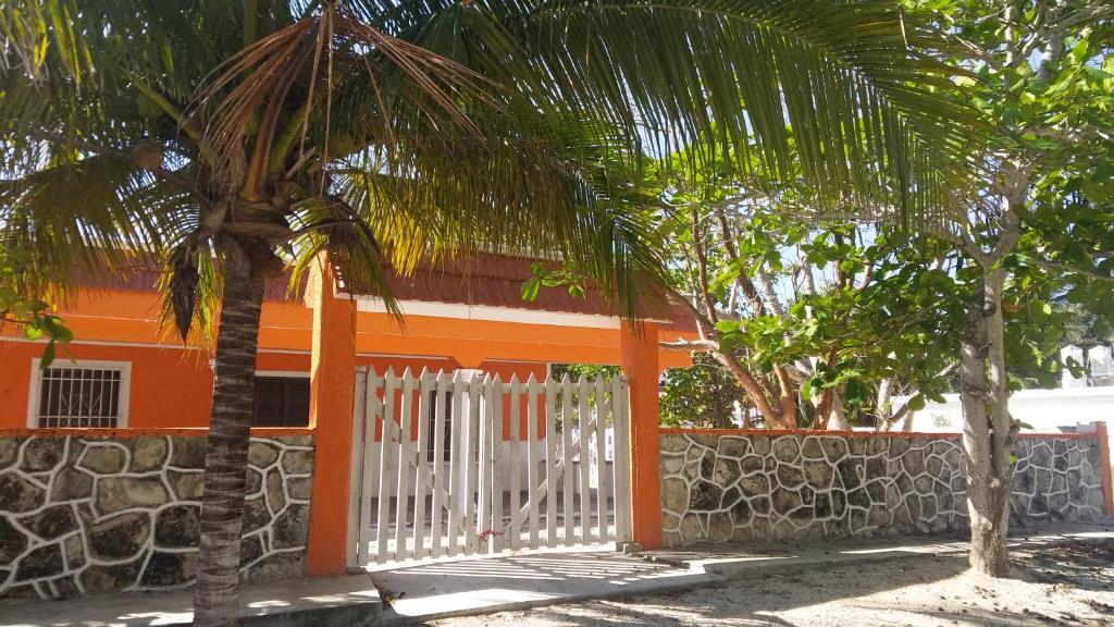 ein orangefarbenes Haus mit einem weißen Tor und einer Palme in der Unterkunft Casa Trujeque in Sisal