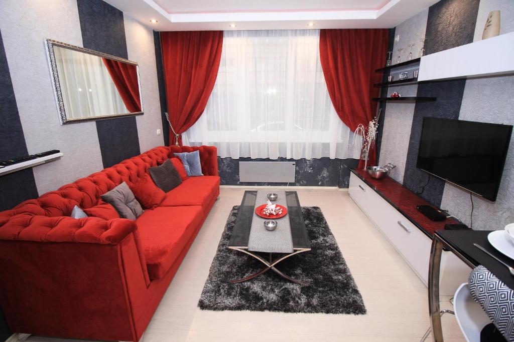 a living room with a red couch and a tv at Apartment Lovac in Belgrade