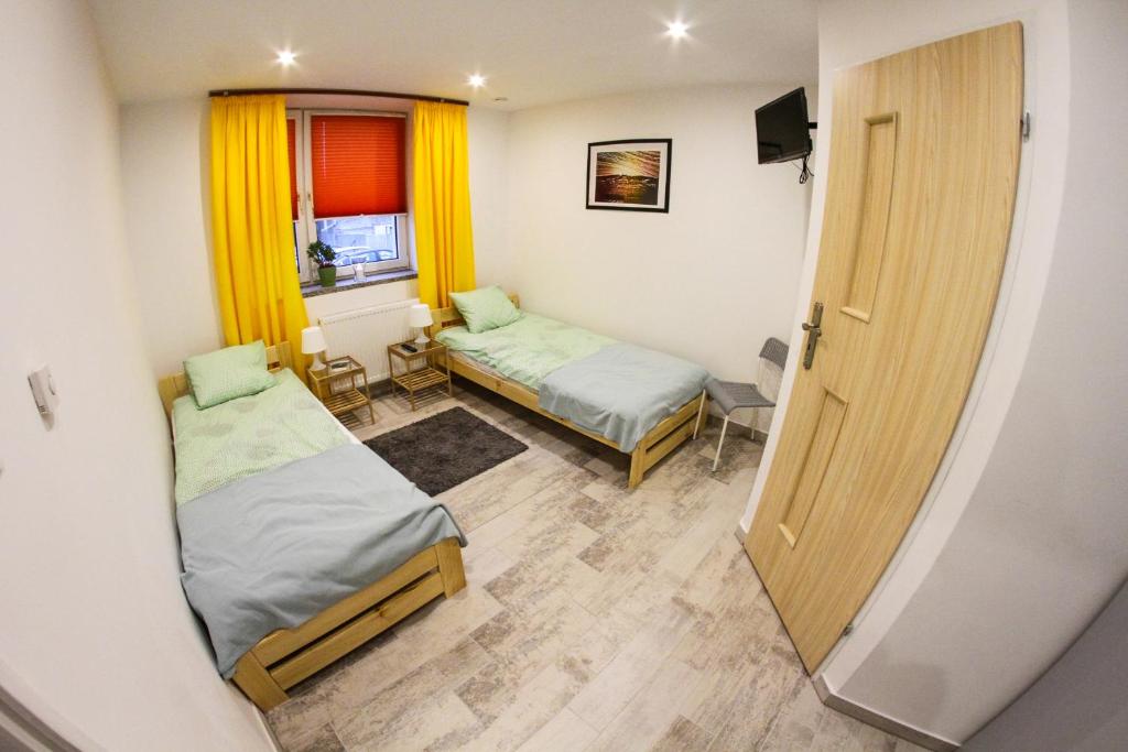 Cette petite chambre comprend 2 lits et une fenêtre. dans l'établissement Na Krzywej, à Chęciny
