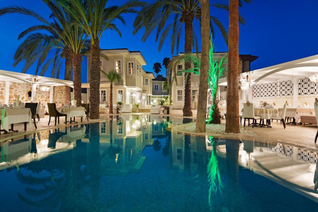 uma piscina num resort com palmeiras em Elegance East Hotel em Antalya