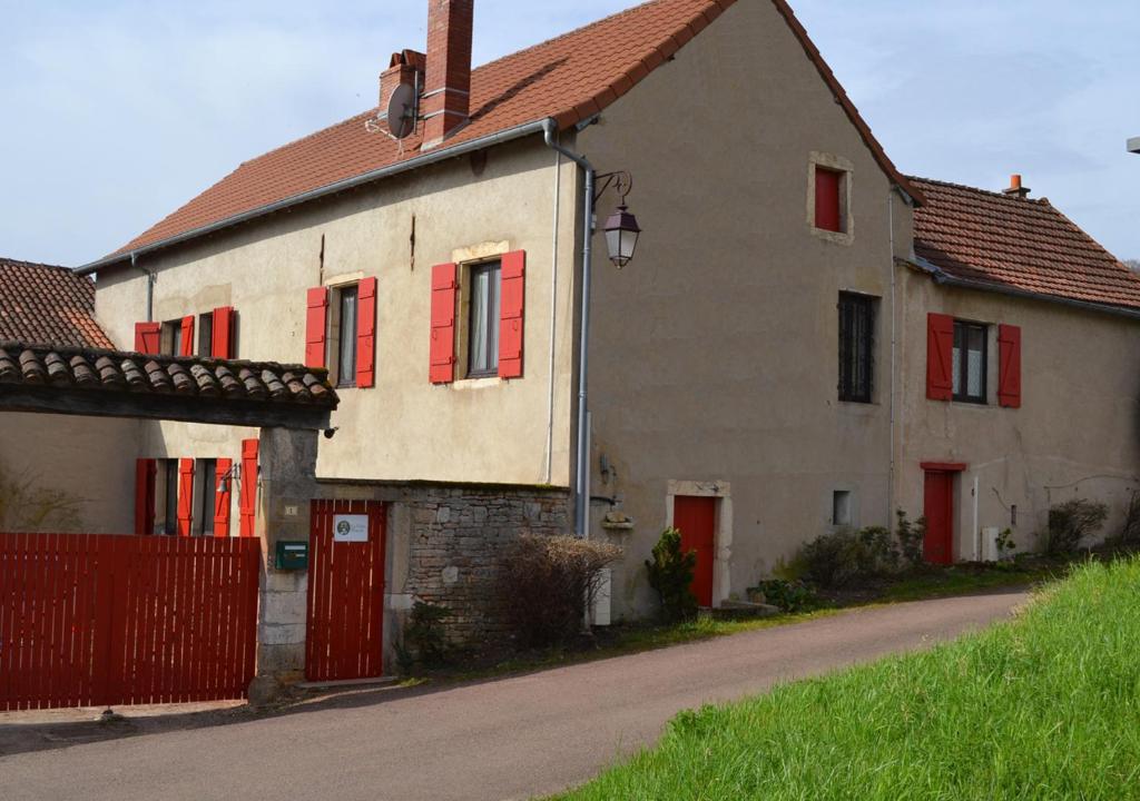 una casa vieja con persianas rojas y un camino en La Follye Mancey en Mancey