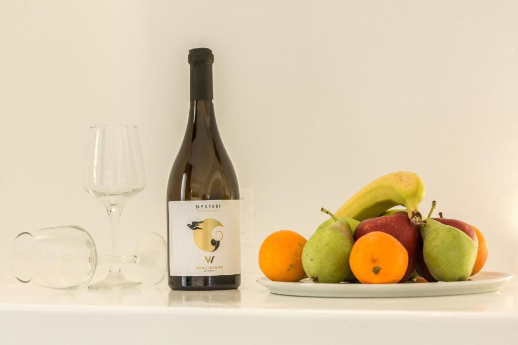 a bottle of wine next to a plate of fruit at Amera Suites in Fira