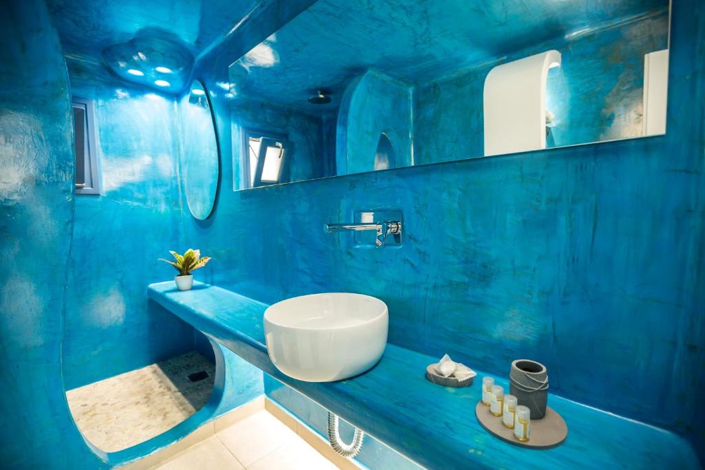 a blue bathroom with a sink and a mirror at Amera Suites in Fira