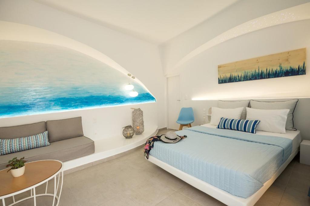 a white bedroom with a bed and a couch at Amera Suites in Fira