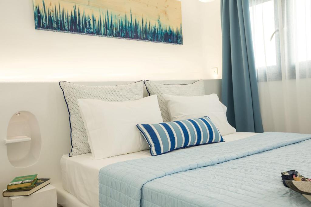 a white bed with blue and white pillows on it at Amera Suites in Fira
