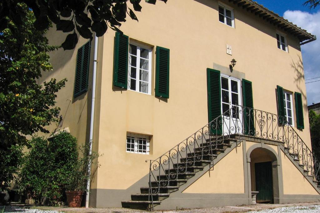 a building with green shuttered windows and a staircase at Casa Orsolini in Lucca