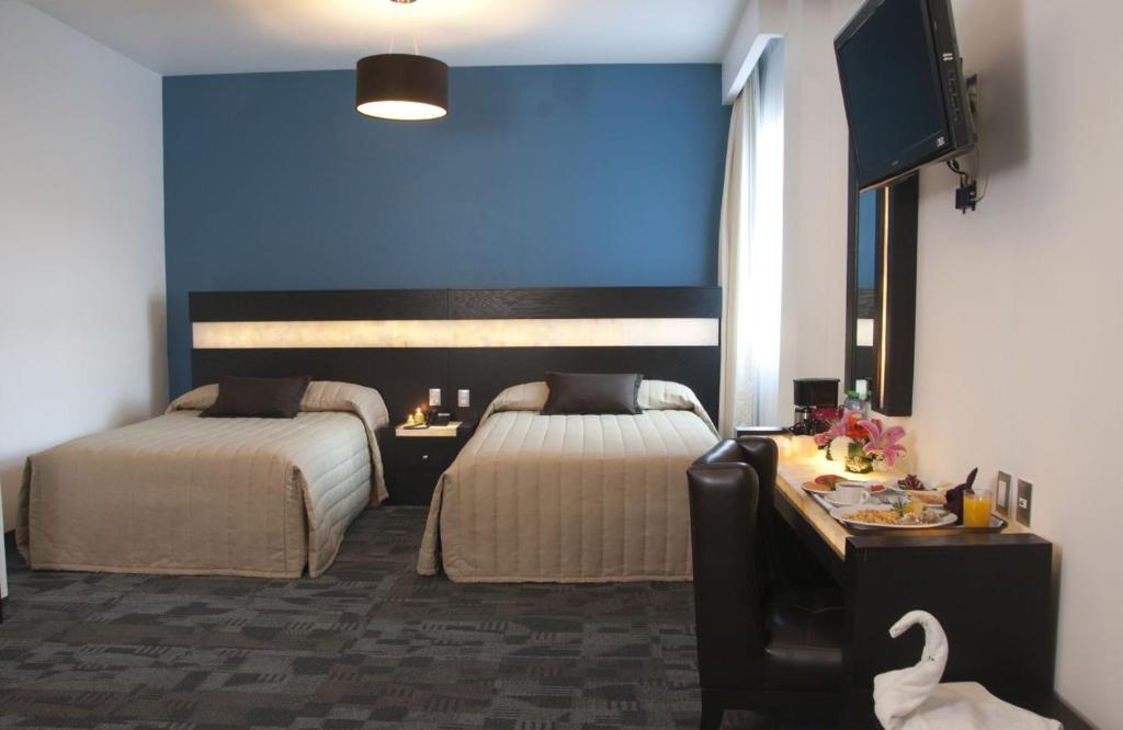 Habitación de hotel con 2 camas y pared azul en Hotel Real Rex en León