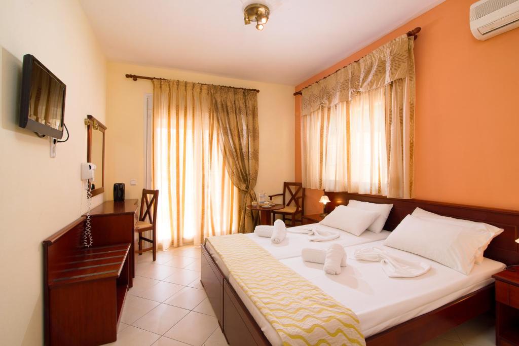 a hotel room with a large bed and a television at Hotel Diamond in Limenaria