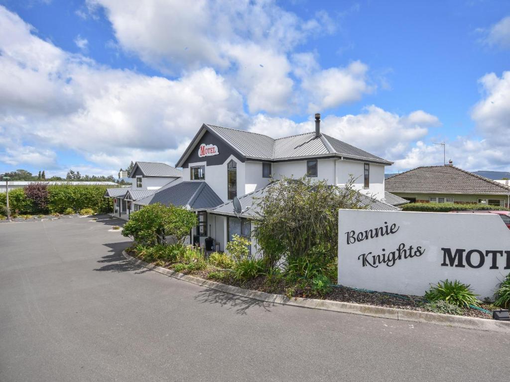 a building with a sign in front of a parking lot at Bonnie Knights Motel Mosgiel in Mosgiel