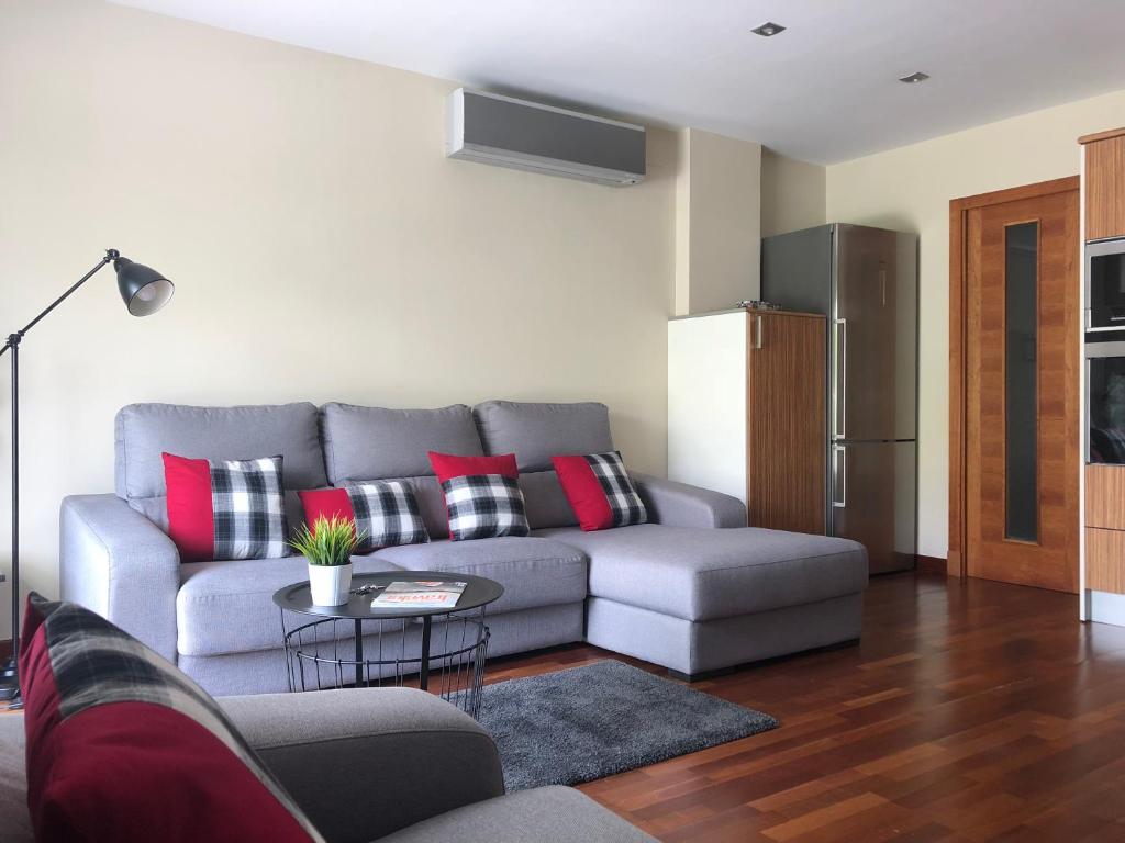 een woonkamer met een grijze bank en rode kussens bij PERSEUS vivienda unifamiliar con terraza y jardín - WIFI - 3 habitaciones - 2 baños in Las Palmas de Gran Canaria