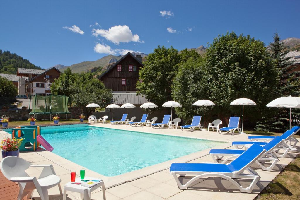 a swimming pool with lounge chairs and umbrellas at Grand Hotel de Valloire et du Galibier in Valloire