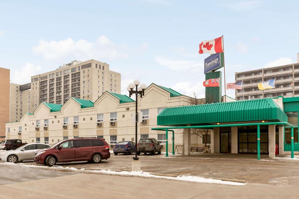 a building with cars parked in a parking lot at Travelodge by Wyndham Winnipeg East in Winnipeg