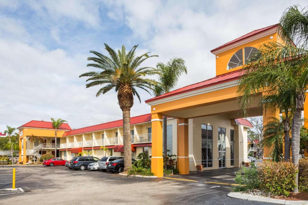 a hotel with a palm tree in front of a parking lot at Days Inn & Suites by Wyndham Port Richey in Port Richey