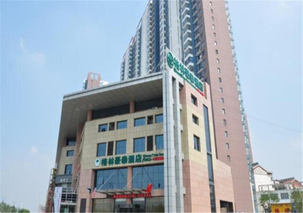 een hoog gebouw met een straatbord ervoor bij GreenTree Inn Shandong Zaozhuang Tengzhou Jiefang Road Business Hotel in Tengzhou