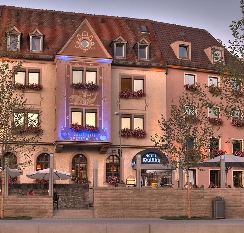 un grand bâtiment avec un panneau bleu devant lui dans l'établissement Hotel & Restaurant Walfisch, à Wurtzbourg