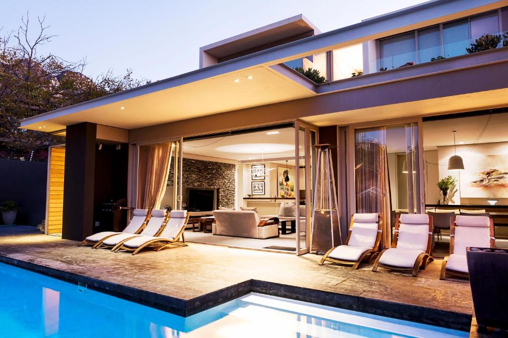 a house with a swimming pool with chairs around it at Blinkwater Villa in Cape Town