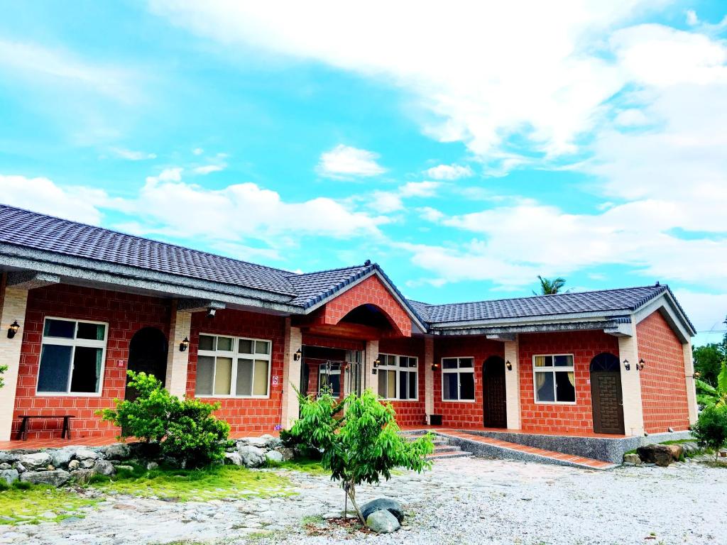 ein rotes Backsteinhaus mit einem Dach in der Unterkunft Jiang Shui Village B&B in Fenglin