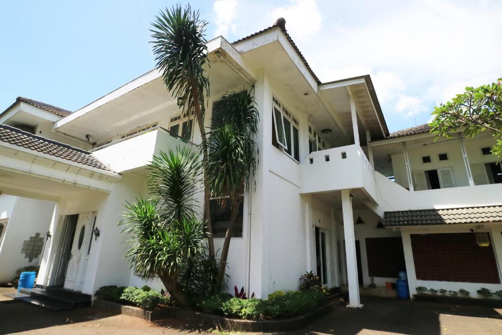 una casa blanca con palmeras delante en Villa Sri Manganti en Yakarta