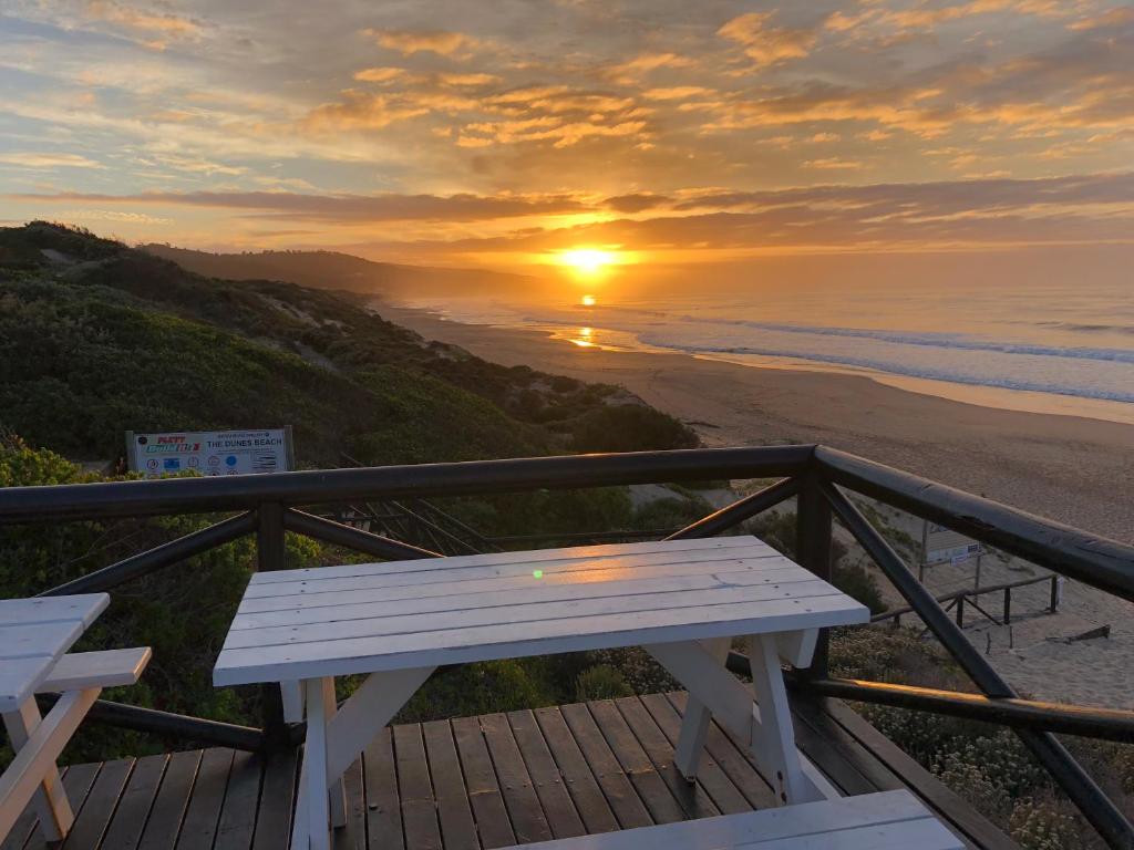 a wooden bench sitting on top of a balcony overlooking the beach at The Dunes Resort 80 & 69 in Plettenberg Bay