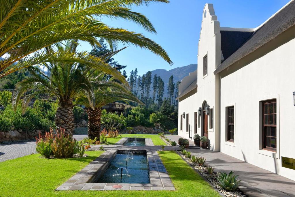 a garden with a water fountain and palm trees at Chamonix in Franschhoek