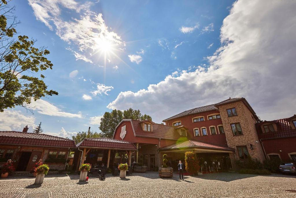 un soleil brille dans le ciel au-dessus d'un groupe de bâtiments dans l'établissement Oławian Hotel, à Oława