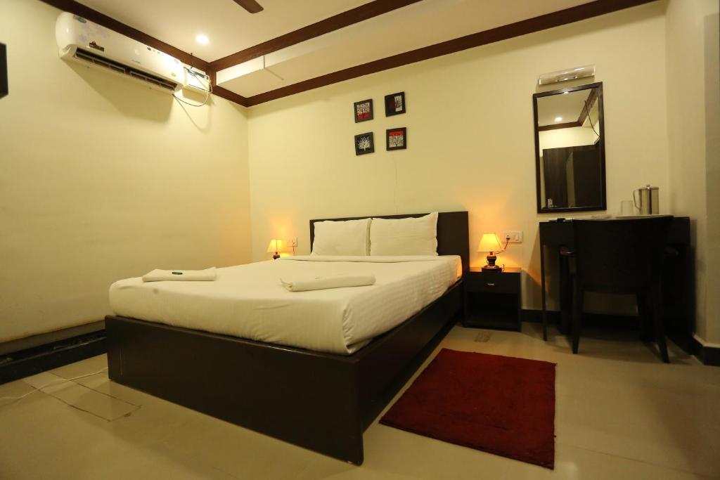 a bedroom with a bed and a table and a mirror at Motel La Grandeur in Mapusa