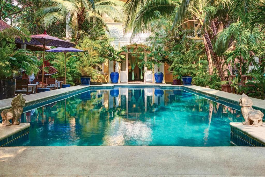 a swimming pool with blue water and palm trees at PAVILION in Phnom Penh