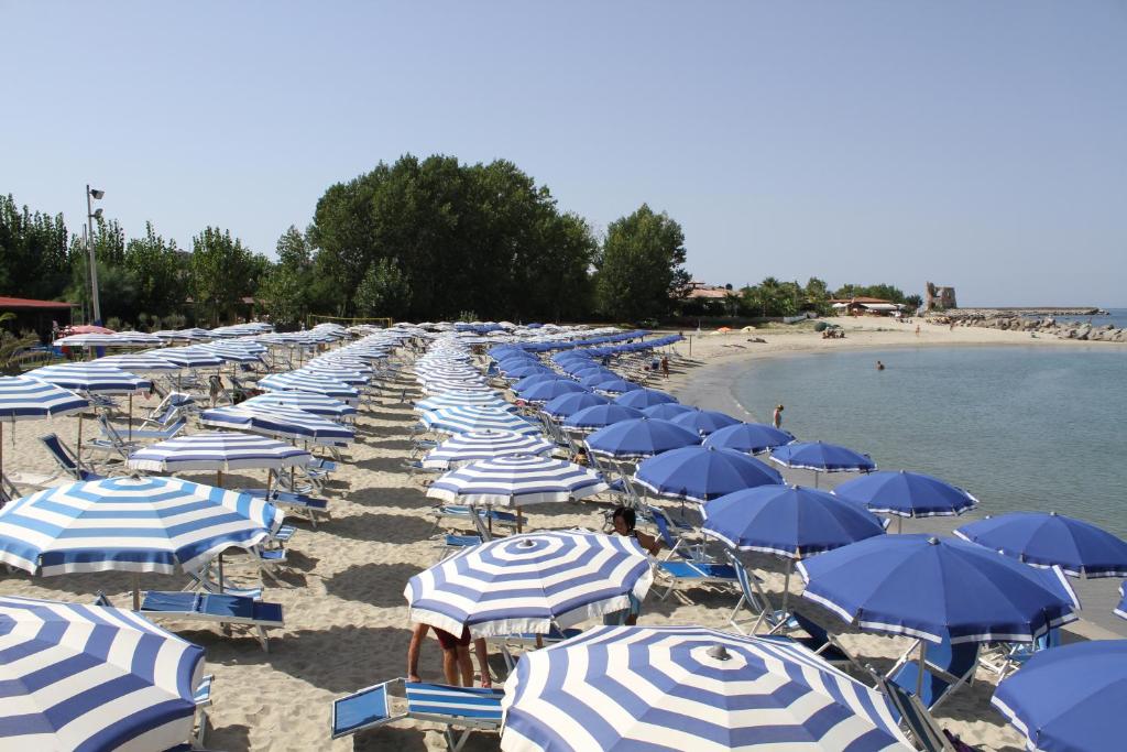 a bunch of blue and white umbrellas on a beach at Green Garden Club in Briatico