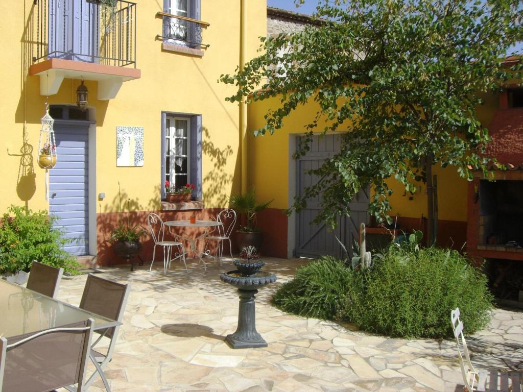 a patio with a table and chairs in front of a yellow building at L'Art de Vivre in Latour-de-France