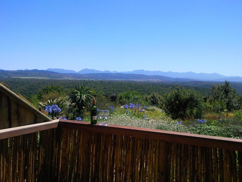 a bottle of wine sitting on a deck with a view at Protea Wilds Retreat in Harkerville