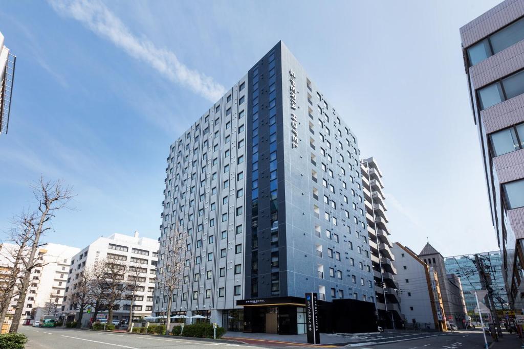 a tall building on a city street with buildings at S-Peria Hotel Hakata in Fukuoka