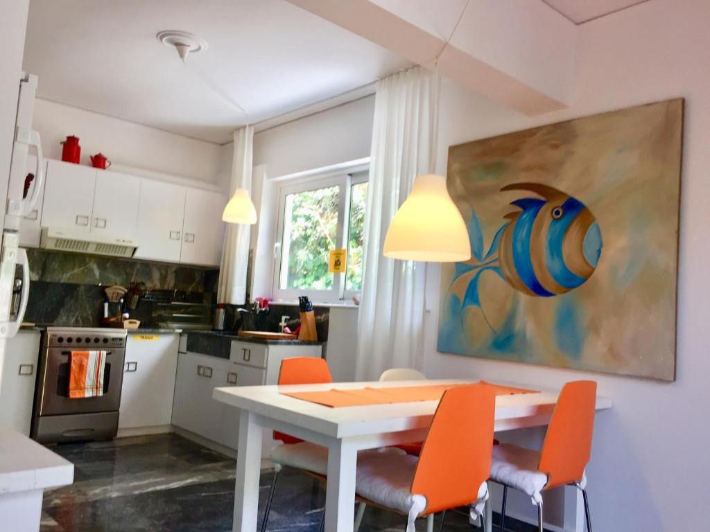 a kitchen with a white table and orange chairs at Flower Garden in Mati