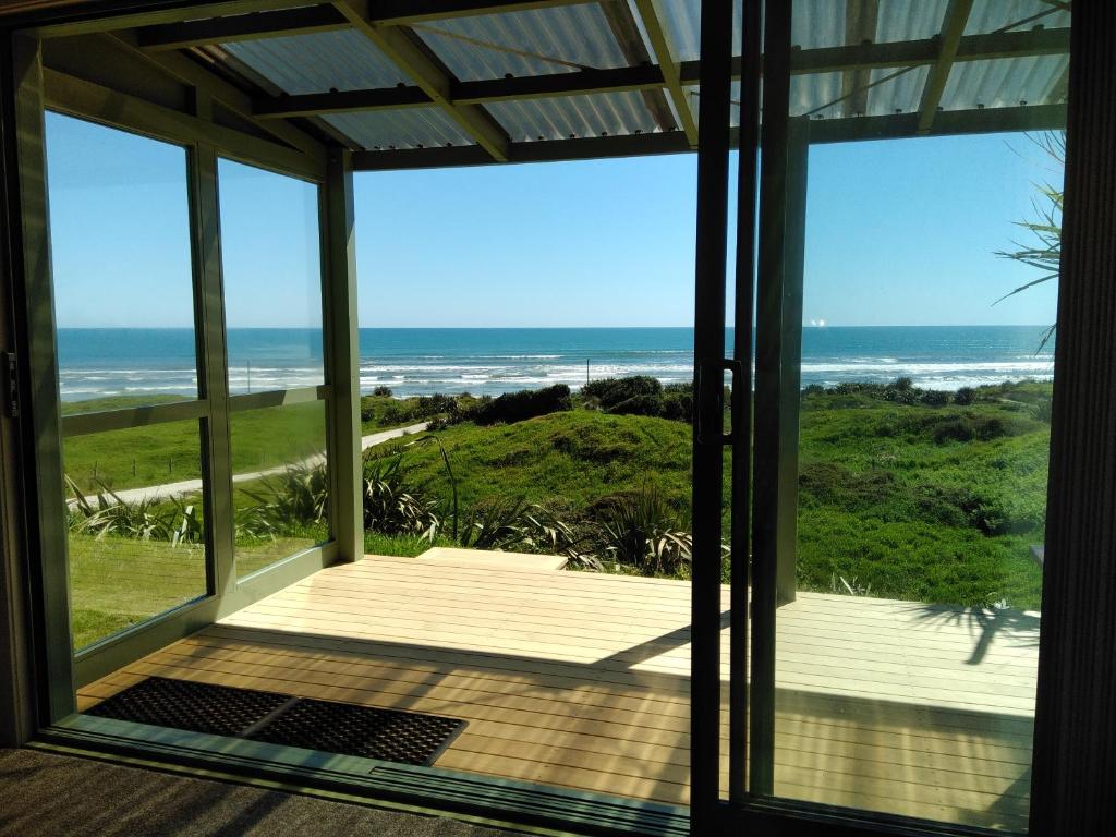 a room with a view of the ocean from a house at Okari Cottage in Cape Foulwind