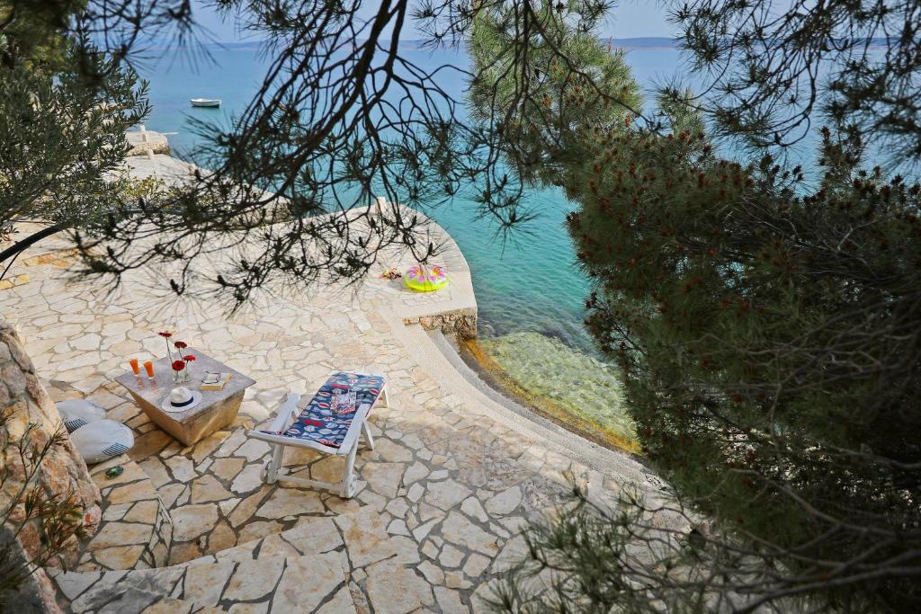 a table and chair next to a body of water at Apartments by the sea in Tribanj-Krušćica