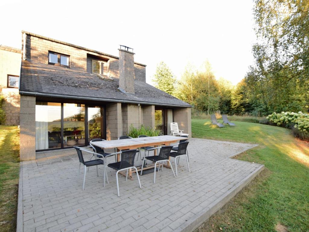 un patio con tavolo e sedie di fronte a una casa di Cozy Villa in Vielsalm with Private Garden a Vielsalm