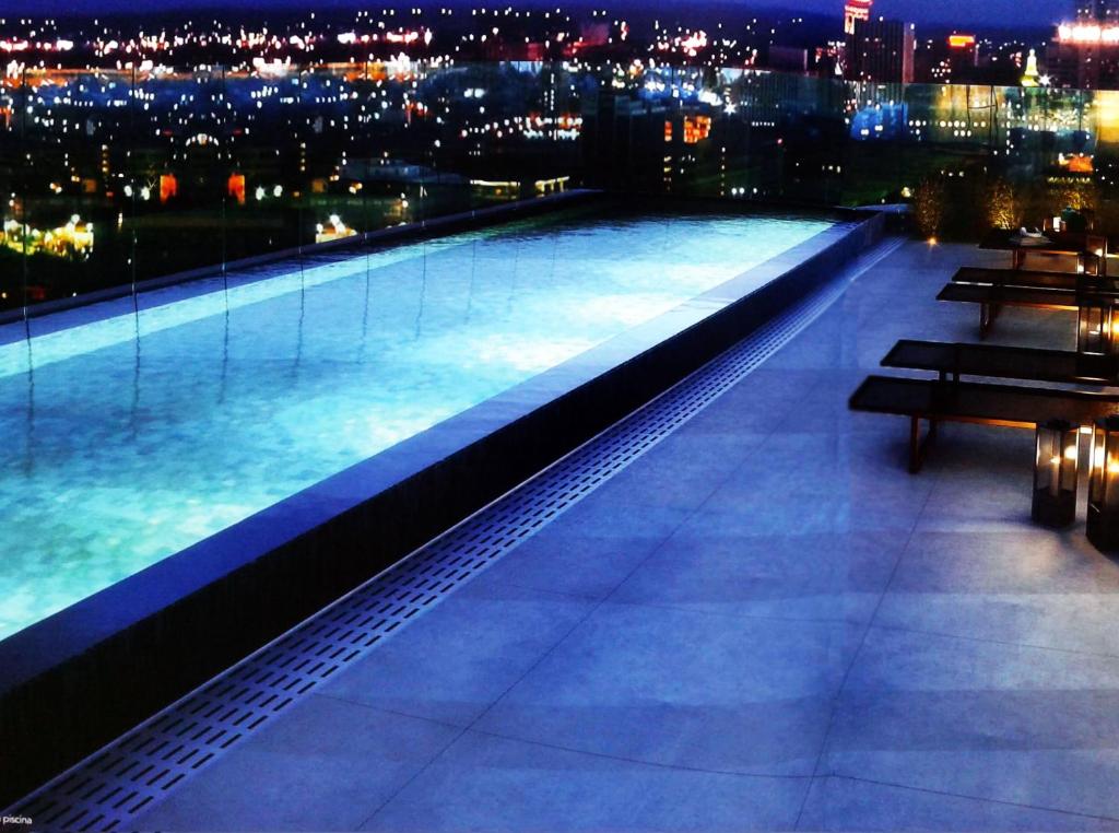 una piscina iluminada en la parte superior de un edificio por la noche en Studio Aconchego, próximo a Rua da Consolação, aos Metros República e Anhangabaú, com ar condicionado, piscina, academia, wifi e varanda, en São Paulo