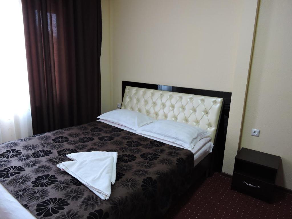 a bedroom with a bed with two white towels on it at Inn Kochevnik in Cholpon-Ata