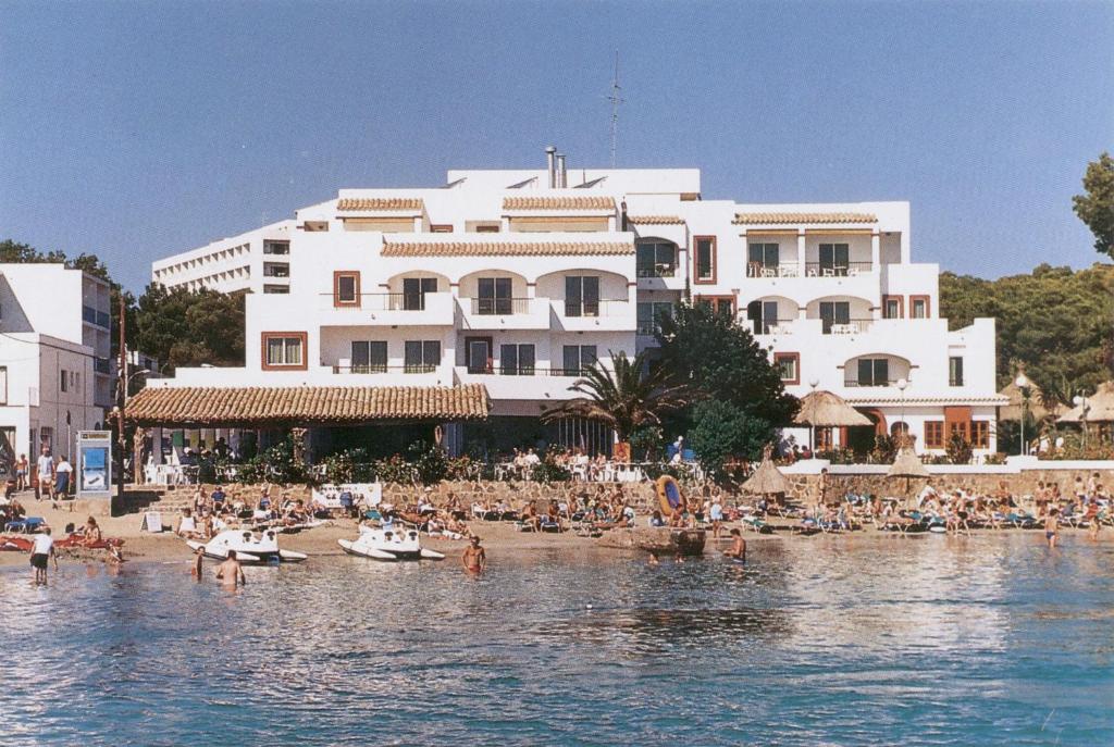 um grupo de pessoas numa praia em frente a um edifício em Apartamentos Playa Es Cana em Es Cana