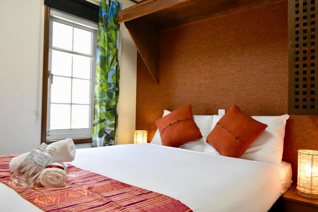 um quarto com uma grande cama branca com janela em Mojo Lodge Hakuba em Hakuba