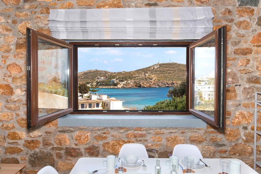 een kamer met een raam met uitzicht op de oceaan bij Syra Suites in Vári