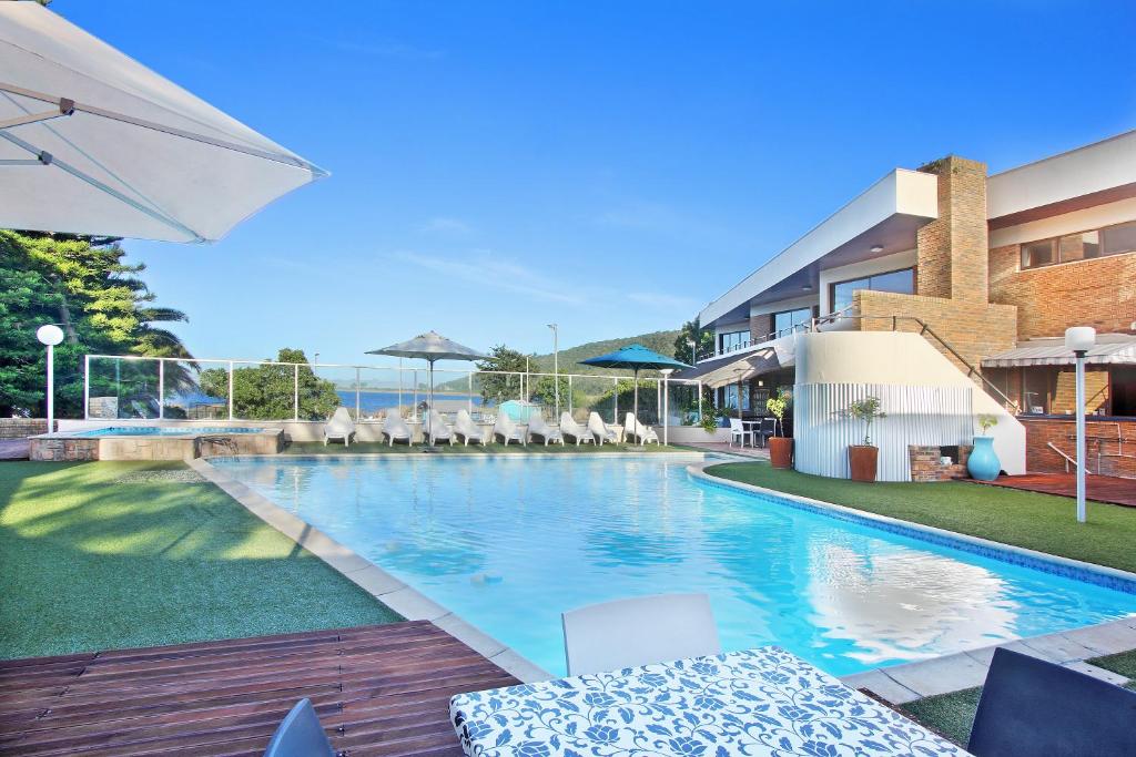 a swimming pool with chairs and an umbrella at Baywater Village in Sedgefield