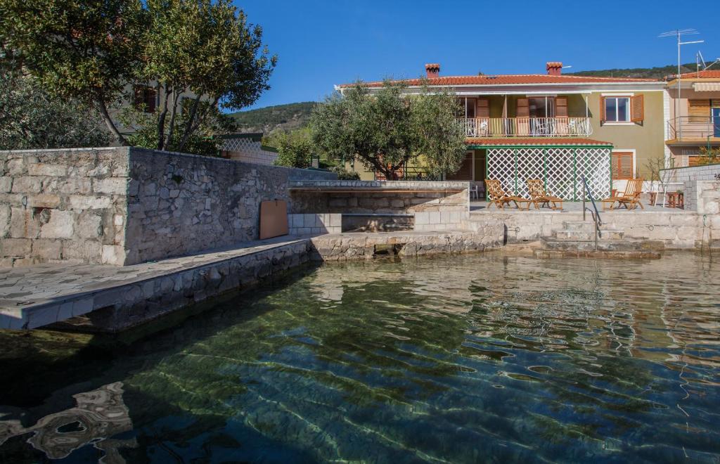 una piscina d'acqua con una casa sullo sfondo di Apartman Solis a Cres