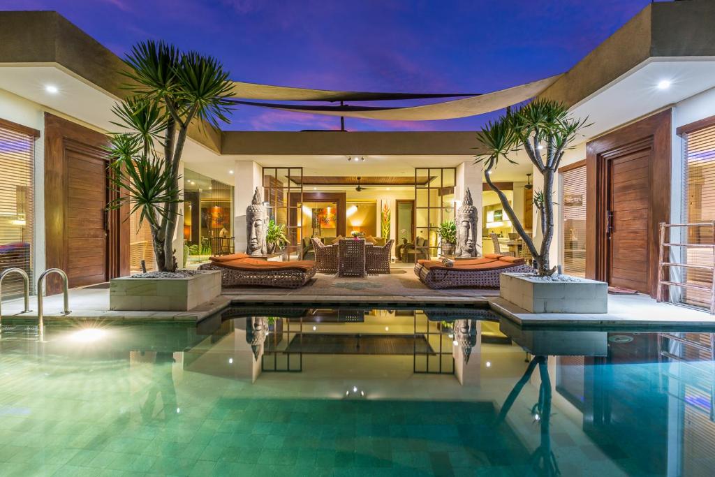 una piscina cubierta en una casa con palmeras en Villa Lisha, en Canggu