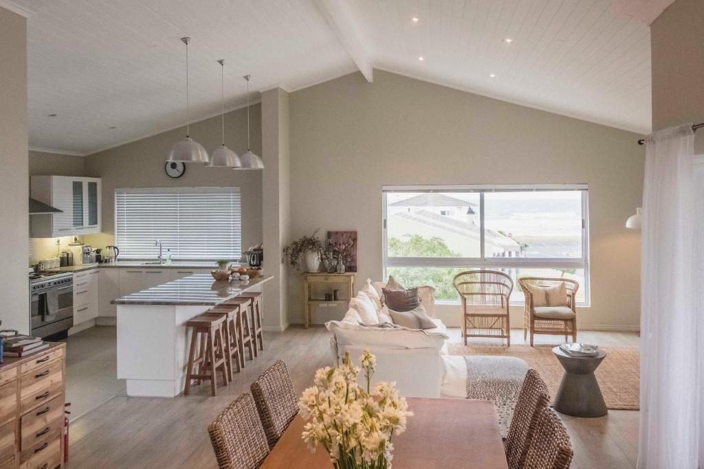 a kitchen and living room with a couch and a table at Hilton Cove Beach House in Melkbosstrand