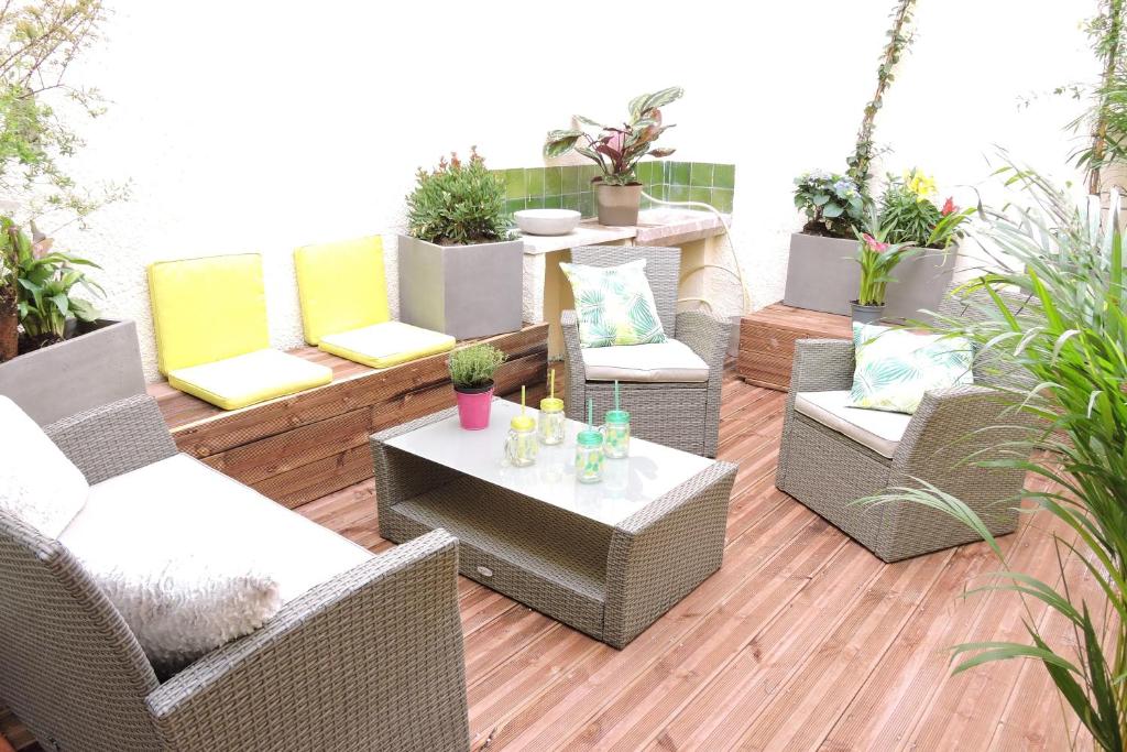 une terrasse avec des chaises et des tables en osier et des plantes en pot dans l'établissement Le Clos Des Orangers, à Collioure