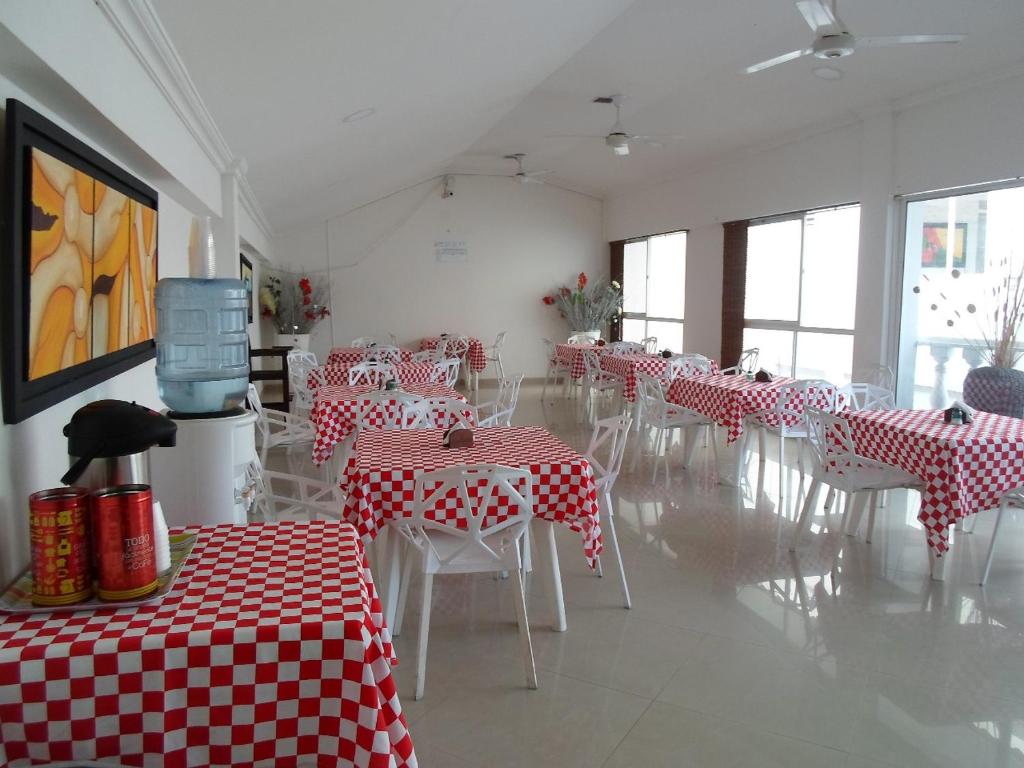 un comedor con mesas y sillas rojas y blancas en Hotel Zamba en Girardot